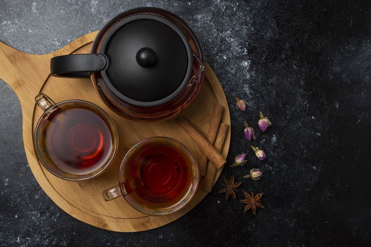 Herbal winter tea in the cups with spices on a wooden board