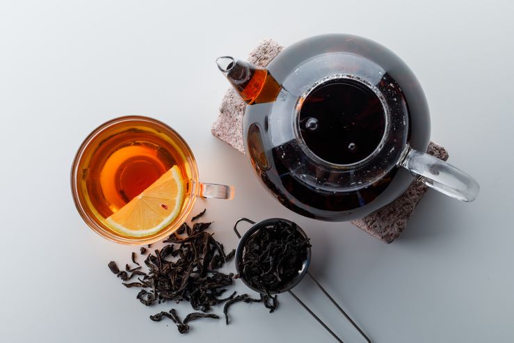 Lemony tea with teapot on brick, strainer, dry tea in a cup