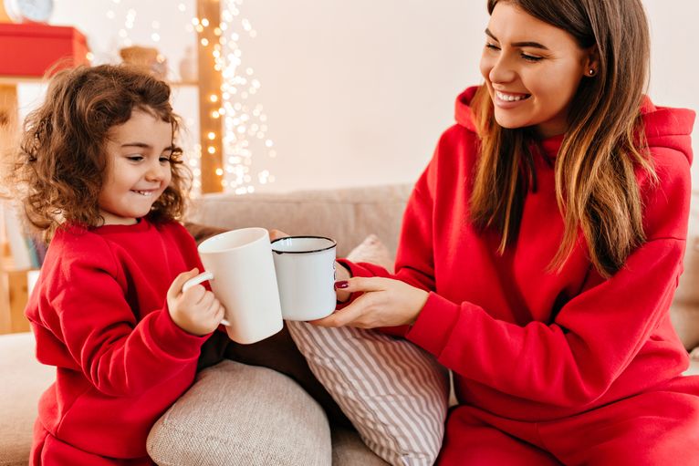 Smiling mother and daughter holding tea cups